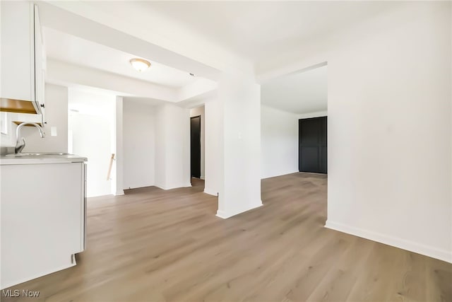 interior space with a sink, baseboards, and light wood-type flooring