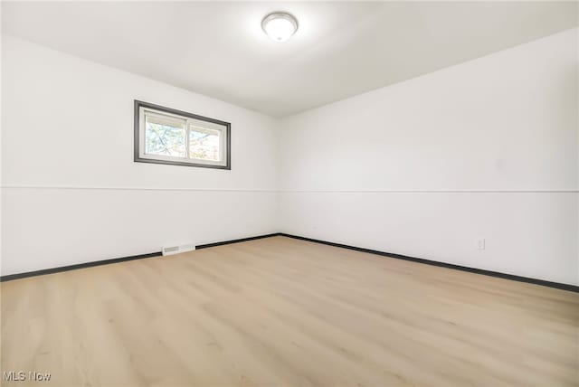 unfurnished room featuring baseboards, visible vents, and wood finished floors