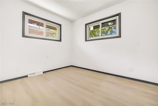 empty room featuring visible vents, baseboards, wood finished floors, and a healthy amount of sunlight