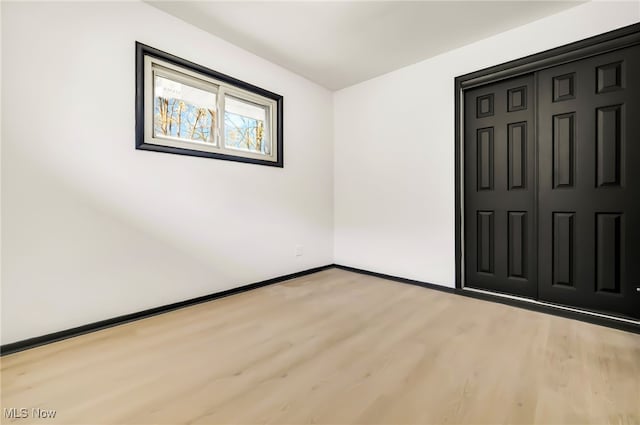 unfurnished bedroom with baseboards, a closet, and light wood-type flooring