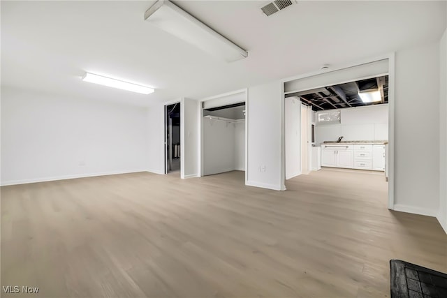 unfurnished bedroom featuring visible vents, light wood-style floors, and baseboards