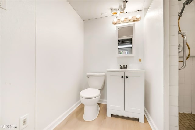 bathroom featuring toilet, baseboards, a tile shower, and vanity