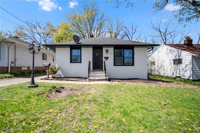 bungalow-style house with entry steps, roof with shingles, stucco siding, and a front lawn
