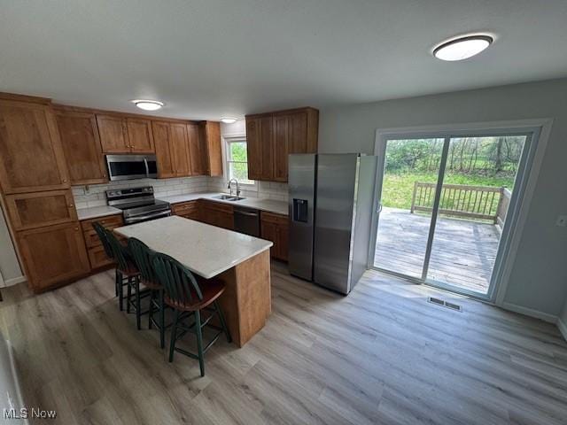 6720 Prior Rd, Nashport, OH 43830 - kitchen with visible vents, appliances with stainless steel finishes, tasteful backsplash, light wood-type flooring, and brown cabinets