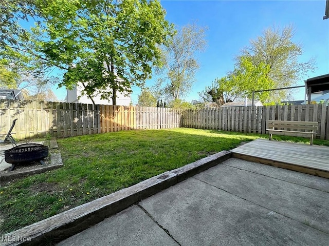 view of yard with a fenced backyard, a fire pit, a patio area, and a deck
