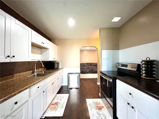 kitchen with dark wood-style flooring, black microwave, arched walkways, a sink, and stainless steel electric range oven