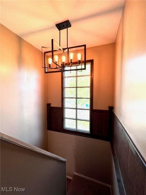 stairway featuring a chandelier and a wainscoted wall