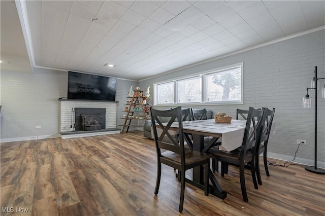 dining room with ornamental molding, wood finished floors, and brick wall