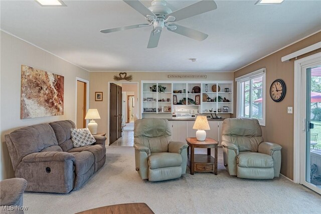 living area featuring crown molding, ceiling fan, and light carpet