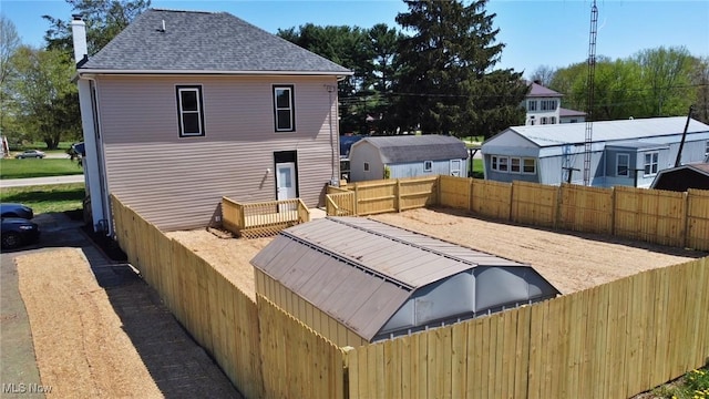 rear view of house featuring a fenced backyard, a chimney, and roof with shingles