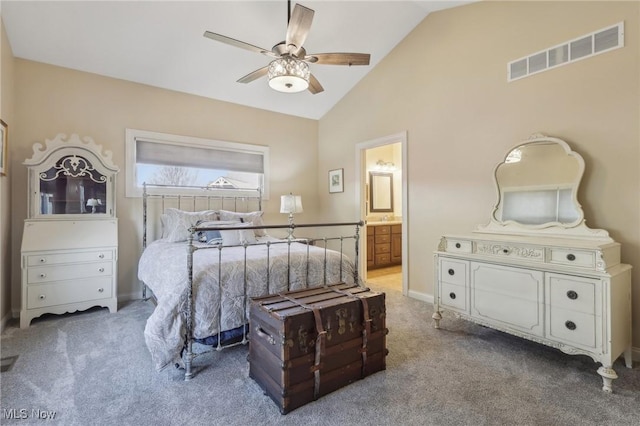 carpeted bedroom with visible vents, baseboards, a ceiling fan, ensuite bath, and vaulted ceiling
