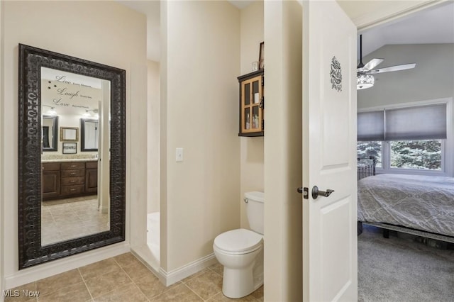 ensuite bathroom featuring a ceiling fan, vanity, baseboards, toilet, and lofted ceiling