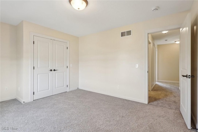 unfurnished bedroom featuring visible vents, carpet, baseboards, and a closet