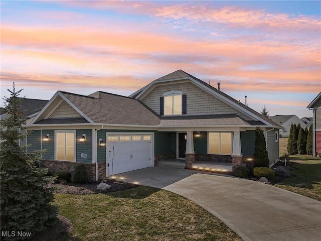 craftsman house featuring a garage, a yard, driveway, and stone siding