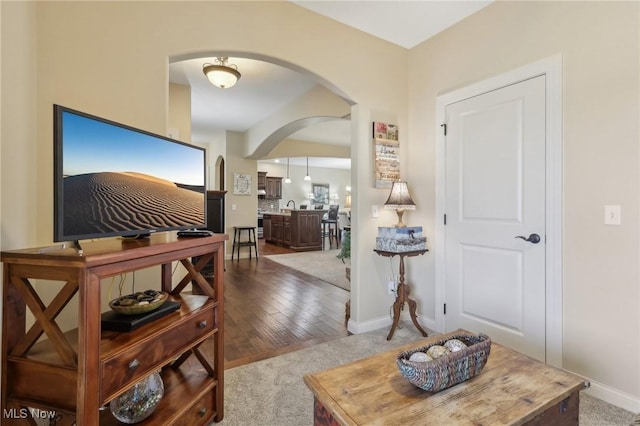 foyer entrance featuring arched walkways, baseboards, and carpet