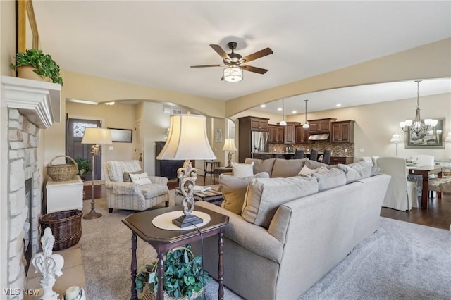 living area with arched walkways, ceiling fan with notable chandelier, and recessed lighting
