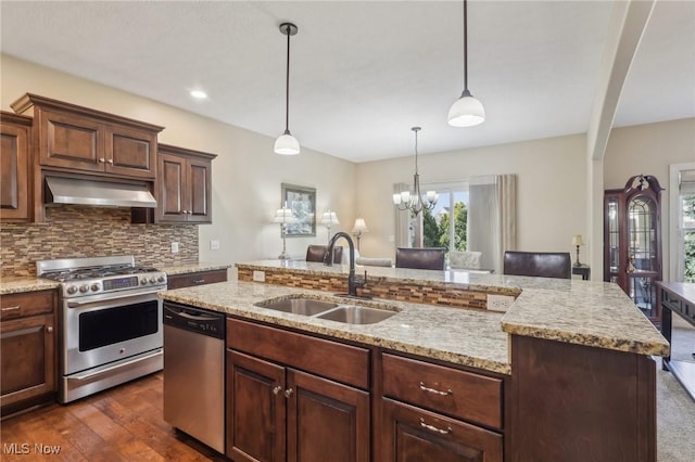kitchen featuring a sink, stainless steel appliances, backsplash, under cabinet range hood, and dark wood-style floors