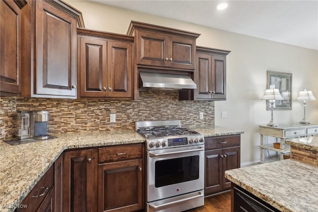 kitchen featuring gas stove, light stone counters, backsplash, and wall chimney exhaust hood