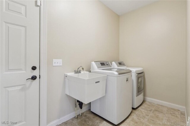 laundry area with laundry area, a sink, baseboards, and washer and dryer