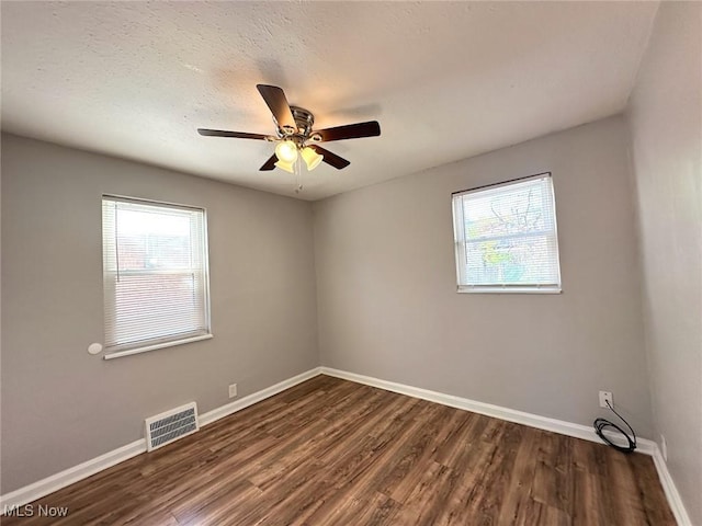 unfurnished room with plenty of natural light, dark wood-type flooring, and visible vents