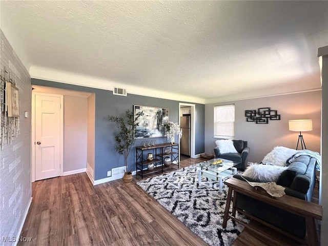 living area featuring a textured ceiling, baseboards, wood finished floors, and visible vents