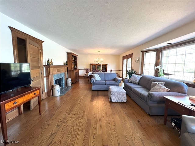 living area with a premium fireplace, a textured ceiling, a chandelier, and wood finished floors