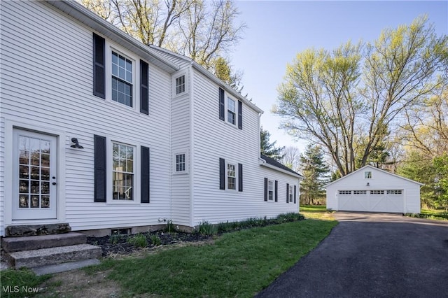 view of side of home with a garage, an outbuilding, entry steps, and a lawn