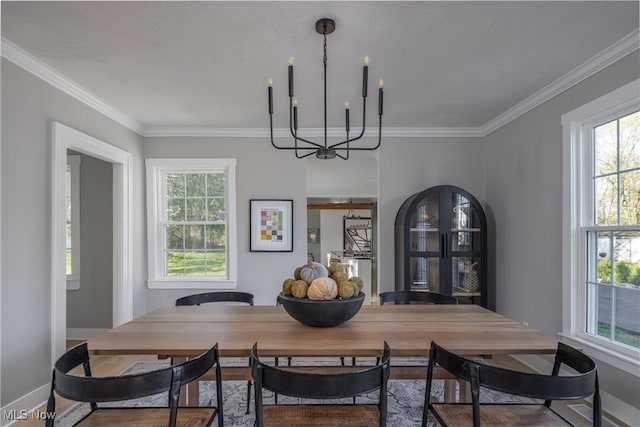 dining room featuring crown molding, baseboards, a wealth of natural light, and a chandelier