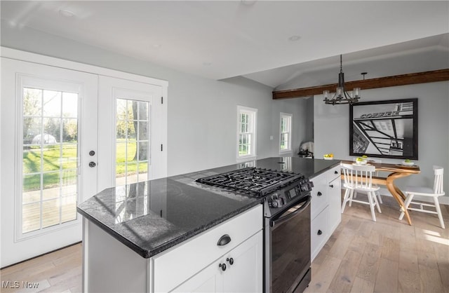 kitchen with vaulted ceiling, light wood-type flooring, white cabinets, black range with gas stovetop, and a chandelier