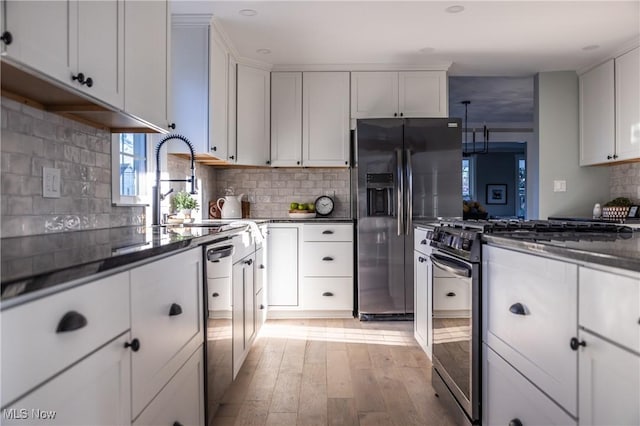 kitchen featuring light wood finished floors, stainless steel range with gas cooktop, white cabinetry, fridge with ice dispenser, and tasteful backsplash