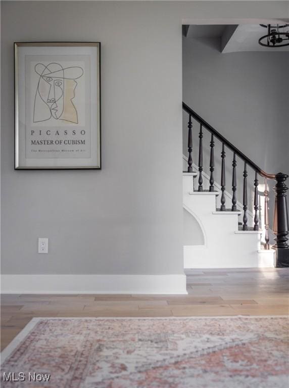 staircase featuring baseboards and wood finished floors