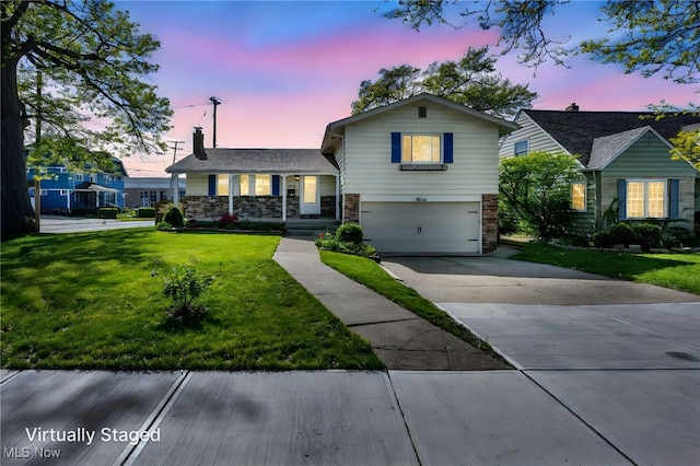 tri-level home with a lawn, a garage, driveway, and a chimney