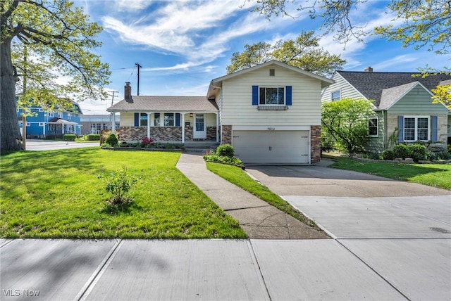 tri-level home featuring a garage, concrete driveway, a front lawn, and brick siding