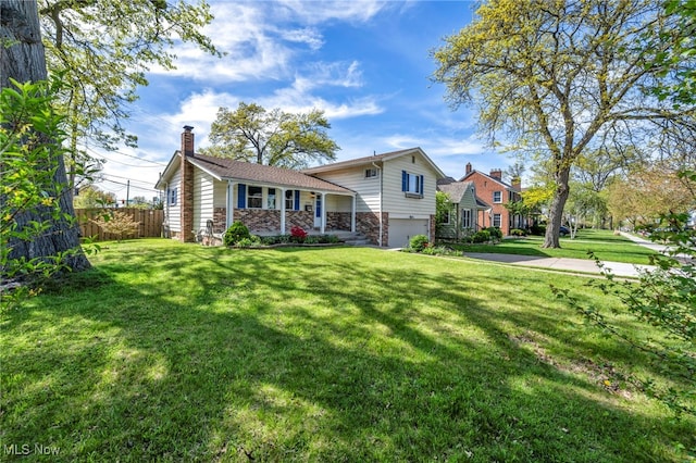 tri-level home featuring a garage, fence, a chimney, and a front yard