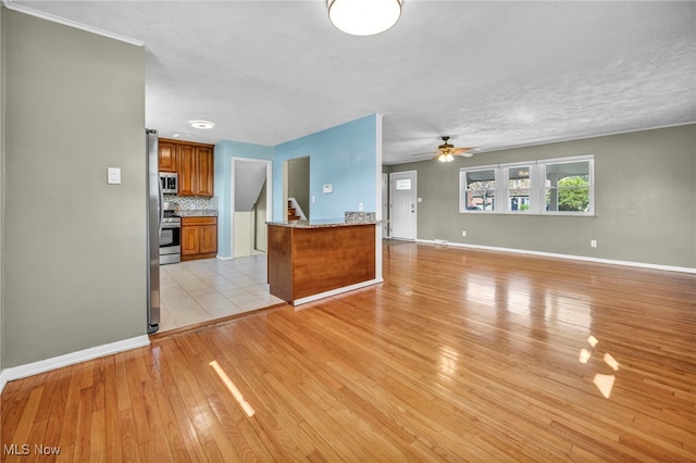 unfurnished living room featuring light wood-type flooring, baseboards, and ceiling fan