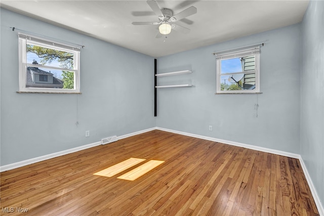 unfurnished room featuring visible vents, baseboards, ceiling fan, and hardwood / wood-style floors