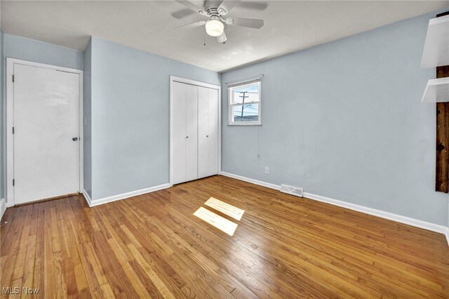 unfurnished bedroom with visible vents, a closet, wood-type flooring, baseboards, and ceiling fan