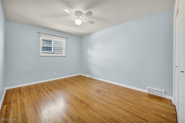 spare room featuring baseboards, hardwood / wood-style flooring, and visible vents