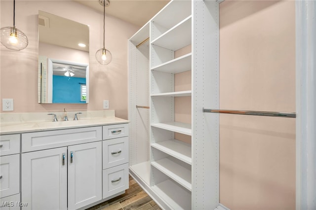 bathroom with a ceiling fan, wood finished floors, and vanity