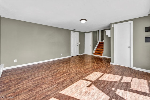 empty room with baseboards, wood finished floors, and stairway