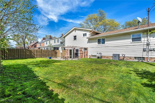 back of property with a lawn, fence, and central AC unit