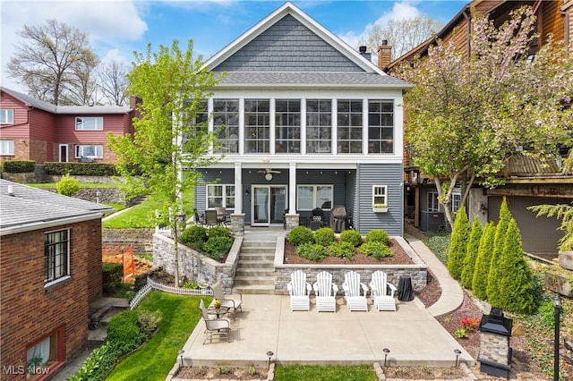 back of house with roof with shingles, stairs, ceiling fan, a chimney, and a patio area
