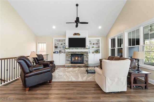 living area with ceiling fan, a stone fireplace, baseboards, wood finished floors, and lofted ceiling