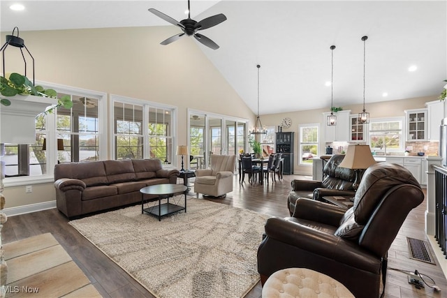 living room featuring high vaulted ceiling, ceiling fan with notable chandelier, recessed lighting, and wood finished floors