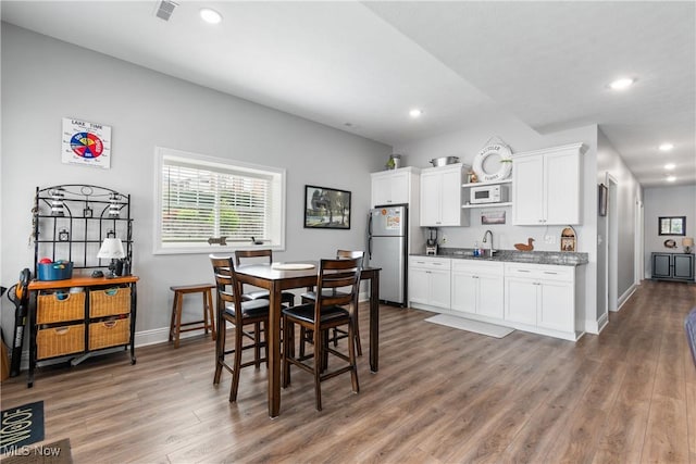dining space with recessed lighting, baseboards, wood finished floors, and visible vents