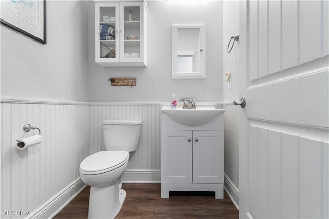 bathroom featuring vanity, toilet, wood finished floors, and a wainscoted wall
