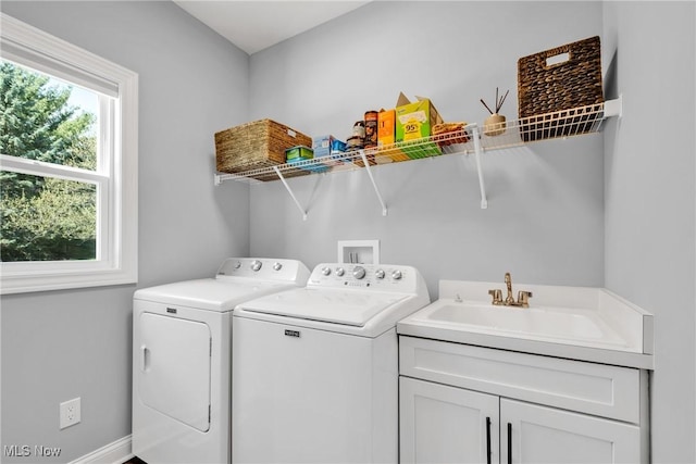 washroom with baseboards, a sink, cabinet space, and washer and dryer