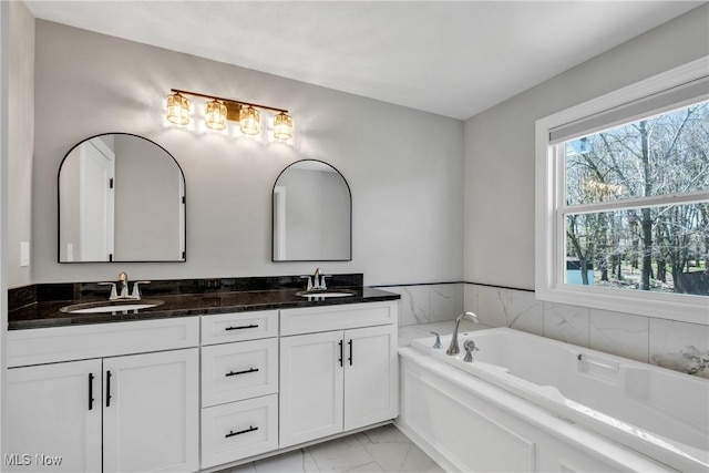 bathroom featuring a sink, double vanity, a bath, and marble finish floor