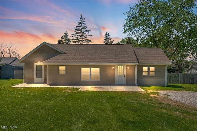 single story home with roof with shingles, a front yard, fence, and a patio area