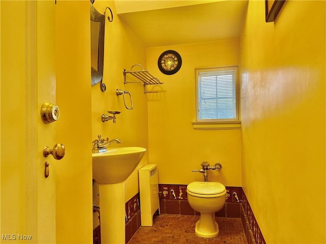 half bath featuring brick floor and toilet
